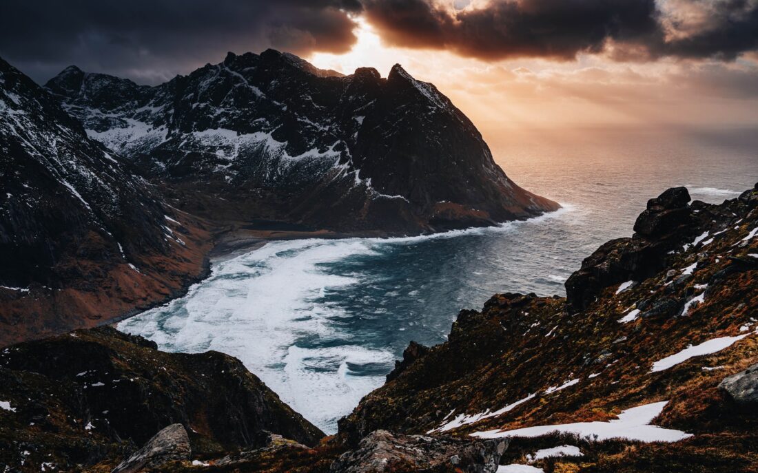 Bay with white surf below the mountain ridge, from above
