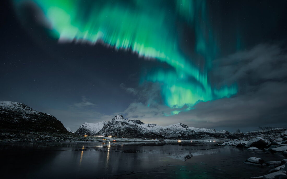 Aurora over the fjord, the village lights below